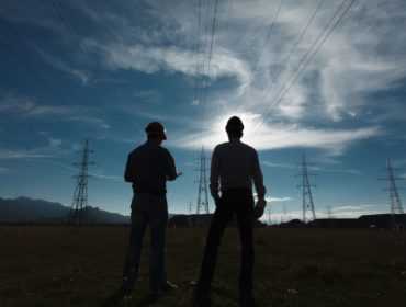 silhouette of two engineers standing at  electricity station